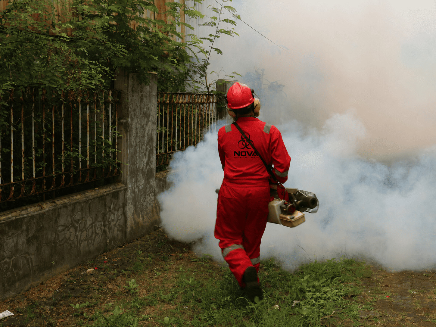 Profesional realizando tratamiento de fumigación en exteriores